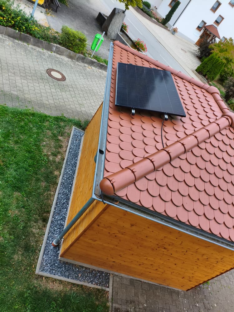 Blick von oben auf das Ziegeldach der Hütte mit einem Solarmodul